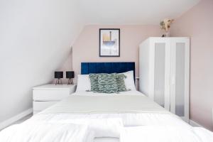 um quarto branco com uma cama azul e branca em Spacious 3 BR Near Walthamstow Station - 10 Min Walk em Londres