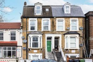 uma velha casa de tijolos com uma porta verde em Spacious 3 BR Near Walthamstow Station - 10 Min Walk em Londres