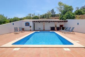 een zwembad voor een wit gebouw met stoelen bij Quinta Azul in Moncarapacho