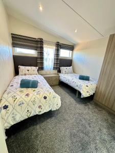 a bedroom with two beds and two windows at Bluebell Lodge, Dog Friendly in South Cerney