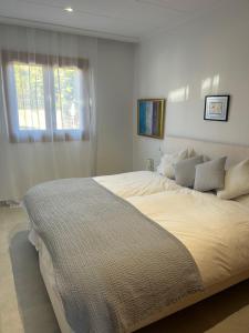 1 cama blanca grande en un dormitorio con ventana en CASA PISCINA DOCTOR FLEMING 51, en Llubí