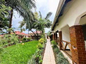 a walkway in front of a house with palm trees at Home Feeling Neneu Lodge in Moshi