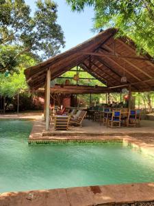 un pabellón con mesa y sillas junto a una piscina de agua en Le Campement en Bamako