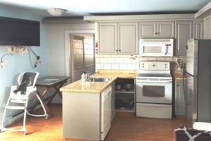 a kitchen with white appliances and a table with a chair at Sunset Cottage, 3 min walk to beach, sleeps 7 in Lambton Shores