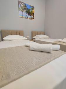 una camera con tre letti con lenzuola bianche di BP Beach Apartment a Golem