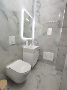 bagno bianco con servizi igienici e lavandino di BP Beach Apartment a Golem