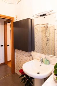 La salle de bains est pourvue d'un lavabo blanc et d'une douche. dans l'établissement Luminoso appartamento con giardino San Bovio, à Peschiera Borromeo