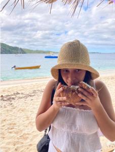 a woman in a hat eating a sandwich on the beach at HCeas guest apartment in Bon Accord