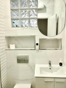 a white bathroom with a sink and a mirror at Soho Boho Apartments - with sunny rooftop terrace and fiber optic internet in Alicante