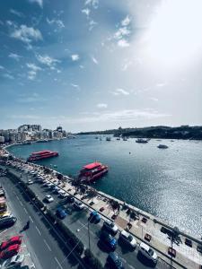 a busy city with cars and a river with boats at Valletta View Apartment - Wish Malta in Sliema