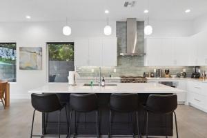 a kitchen with a large white island with black chairs at Desert Blue Rose with Pool in Phoenix