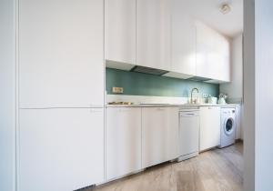 eine Küche mit weißen Schränken, einer Waschmaschine und einem Trockner in der Unterkunft EXCLUSIVE TRIPLEX WITH PRIVATE TERRACE in Sevilla