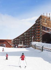 2 personnes à skis dans la neige devant un bâtiment dans l'établissement Hôtel Club mmv Les Mélèzes ****, à Arc 2000