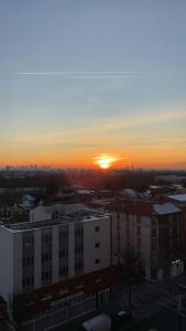 ein Sonnenuntergang über einer Stadt mit einem großen Gebäude in der Unterkunft Appartement 2 chambre avec une vue magnifique de tout Paris, 10min de stade de France in Épinay-sur-Seine