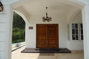 a large wooden door in a building with an archway at Pear Tree Luxe Entire 3BHK Mansion in Kotagiri