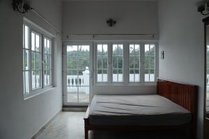 a bedroom with a bed in a room with windows at Pear Tree Luxe Entire 3BHK Mansion in Kotagiri
