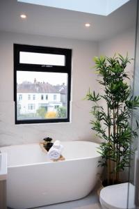 baño con bañera blanca y ventana en Stylish Skylight Room in a Luxury House en Catford