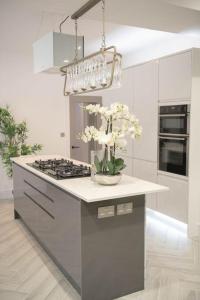 una cocina con fogones y un jarrón con flores blancas en Stylish Skylight Room in a Luxury House en Catford