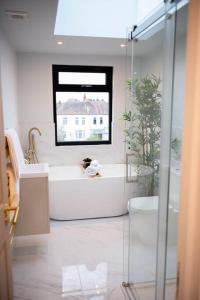 a white bathroom with a tub and a window at Stylish Skylight Room in a Luxury House in Catford