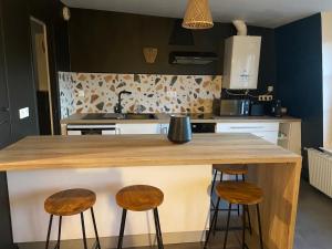 a kitchen with a wooden counter and three stools at Appartement centre ville Caen Vaugueux in Caen