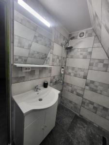 Baño blanco con lavabo y espejo en Cabana Vânătorilor A Frame Green, en Văliug