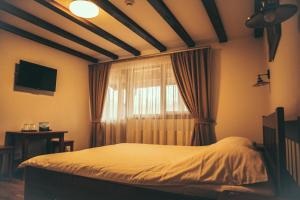 a bedroom with a bed and a window with curtains at Dorul Pescarului in Curtea de Argeş