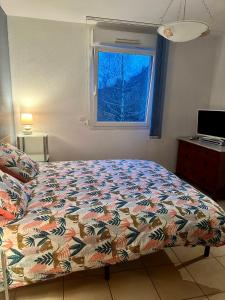 a bedroom with a bed with a colorful comforter and a window at Retour aux sources in Ventron