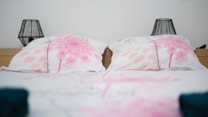 two pink and white pillows on a bed at Appartement en rez-de-chaussée avec jardin in Saint-Genis-Laval