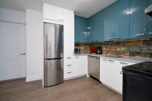 Una cocina con gabinetes blancos y un refrigerador de acero inoxidable. en The Cozy Country Den, en Quebec