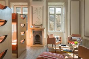 a living room with a fireplace and a table and chairs at Serenata Hostel Coimbra in Coimbra