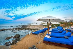 a row of blue chairs and umbrellas on a beach at VISTA ENCANTADA AT HACIENDA ENCANTADA & SPA RESORT- apartment in Cabo San Lucas