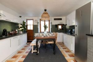 une cuisine avec des placards blancs et une table en bois dans l'établissement Gîte Au Moulin de Bougnon Calme et Dépaysement en Haute-Saône, 