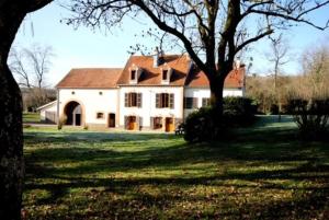 une grande maison blanche avec un arbre dans la cour dans l'établissement Gîte Au Moulin de Bougnon Calme et Dépaysement en Haute-Saône, 