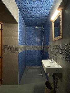 een blauwe betegelde badkamer met een wastafel en een douche bij Chalet Berbère in Essaouira