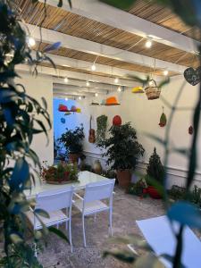 une table et des chaises blanches dans une pièce ornée de plantes dans l'établissement Suite Battisti 7, à Lecce