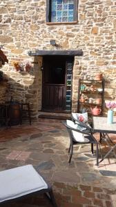 een patio met stoelen, een tafel en een stenen muur bij La Casina de Asturias in Mieres