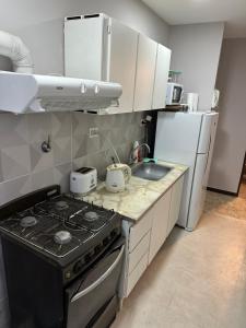 a kitchen with a stove and a refrigerator at Paseo Costero Apart in Comodoro Rivadavia