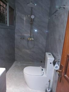 La salle de bains est pourvue d'une douche et de toilettes blanches. dans l'établissement Résidence Wendyna, à Ouagadougou