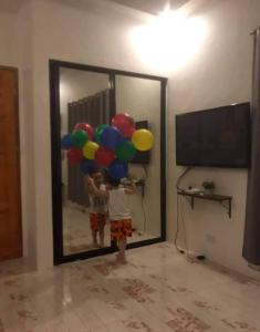 a young boy holding balloons in front of a mirror at Jean apartments in Panglao