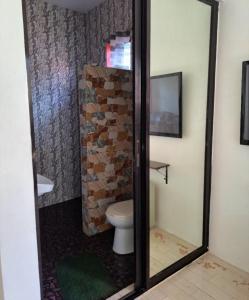 a bathroom with a toilet and a brick wall at Jean apartments in Panglao