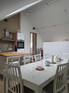 un tavolo bianco e sedie in cucina di Gîte "Aux Pieds des Ar'den" la chambre 1 est fermée et la chambre 2 est dans le hall de nuit séparée par un rideau a Houyet