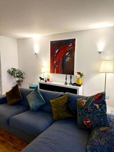 Luxury apartment in Canary Wharf في لندن: أريكة زرقاء في غرفة المعيشة مع لوحة