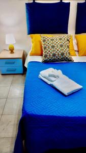a blue bed with a blue blanket and yellow pillows at DGS APARTHOTEL in Trapani