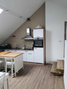 a kitchen with white appliances and a wooden floor at Gîte "Aux Pieds des Ar'den" la chambre 1 est fermée et la chambre 2 est dans le hall de nuit séparée par un rideau in Houyet