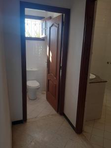 uma casa de banho com um WC e uma porta de madeira em Maison á la campagne em El Guecheïne