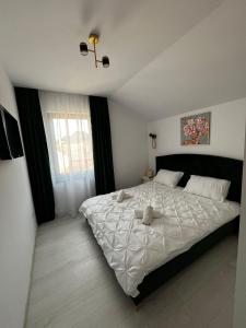 una camera da letto con un grande letto con lenzuola bianche di Gold Tag Apartament a Timişoara