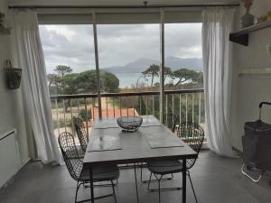a table and chairs in a room with a large window at T2 VUE MER accès plage in Calvi