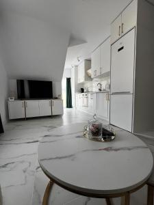 a white kitchen with a table and a white refrigerator at Gold Tag Apartament in Timişoara