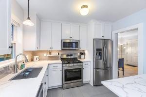 a kitchen with white cabinets and a stainless steel refrigerator at Skyline Blue House in Greenwood in Seattle