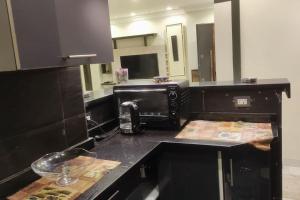 a kitchen with a black counter top with a microwave at Comfortable softness in Cairo